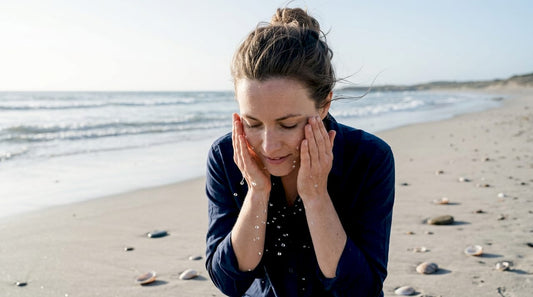 Eine Frau erfrischt sich am Strand, indem sie ihr Gesicht mit Meerwasser wäscht.
