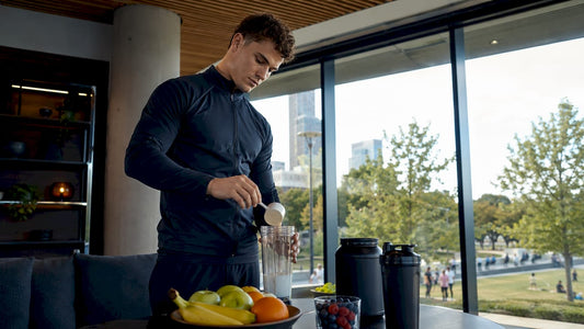 Ein Sportler bereitet sich in der Küche einen Eiweißshake zu.